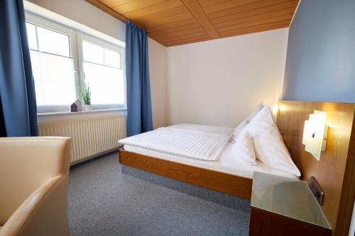 ein kleines Schlafzimmer mit einem Bett und einem Fenster in der Unterkunft Gästehaus am Landhaus Friedrichsfehn in Edewecht