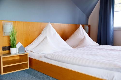 ein Schlafzimmer mit einem großen Bett mit weißen Kissen in der Unterkunft Gästehaus am Landhaus Friedrichsfehn in Edewecht