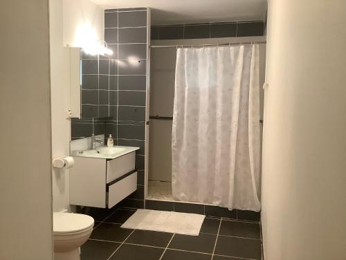 a bathroom with a white shower curtain and a toilet at VILLA ALIZEE APPARTEMENT 2 in Sainte-Rose