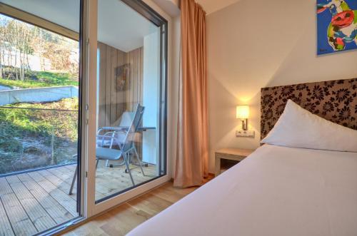 a bedroom with a bed and a balcony at Alpin & Seeresort Top 10 - by Alpen Apartments in Zell am See