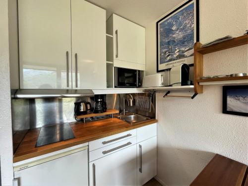 eine kleine Küche mit weißen Schränken und einem Waschbecken in der Unterkunft Studio Les Menuires, 1 pièce, 3 personnes - FR-1-452-281 in Les Menuires