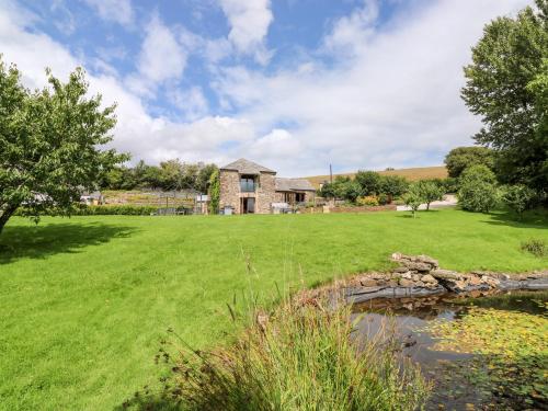 a grassy field with a house and a pond at Birchenhayes in Saltash