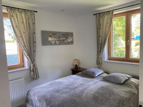 a bedroom with a bed and two windows at Gastuna Suites-Familienapartment in Bad Hofgastein