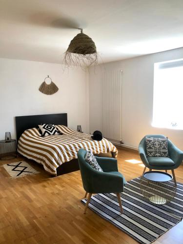 - une chambre avec un lit, deux chaises et un tapis dans l'établissement AU DOMAINE DES OISEAUX ses chambres sa gloriette insolite face à l'étang bucolique, à Vandré