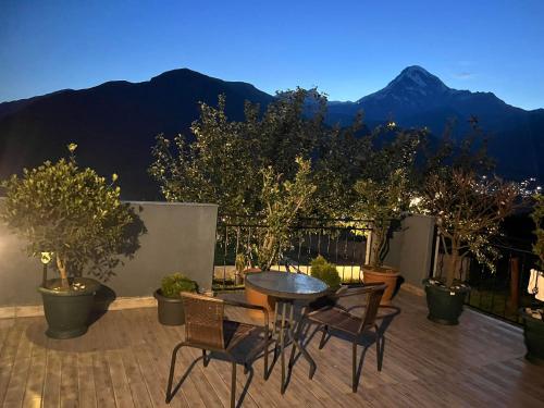 a patio with a table and chairs and mountains at UP Holiday Home in Stepantsminda