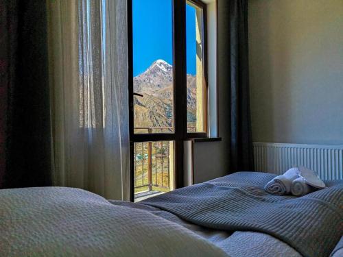 a bedroom with a bed and a window with a mountain view at UP Holiday Home in Stepantsminda