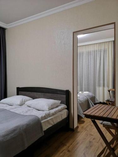 a bedroom with a bed and a mirror and a table at UP Holiday Home in Stepantsminda