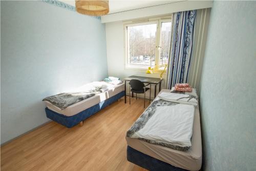 Zimmer mit 2 Betten, einem Schreibtisch und einem Fenster in der Unterkunft Cozy budget room w/ balcony in shared apartment in Vantaa