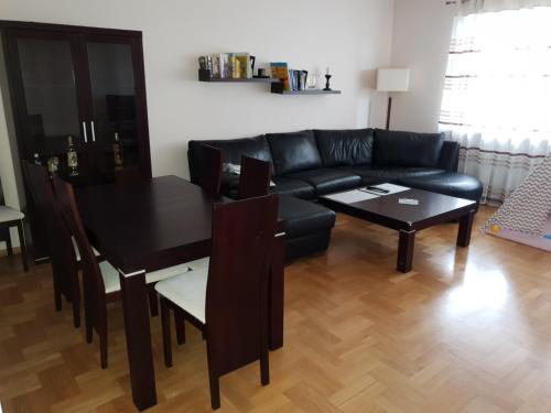 uma sala de estar com um sofá preto e uma mesa em Apartament Alutka em Cracóvia