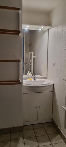 La salle de bains est pourvue d'un lavabo blanc et d'un miroir. dans l'établissement Grand 3 pièces cosy à SuperDévoluy (05) - Plein Sud, au pied des pistes, à Saint-Étienne-en-Dévoluy