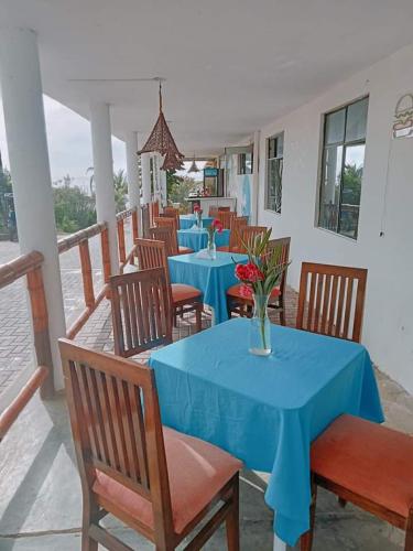 a restaurant with blue tables and chairs with a vase of flowers at La palmera zorritos in Tumbes