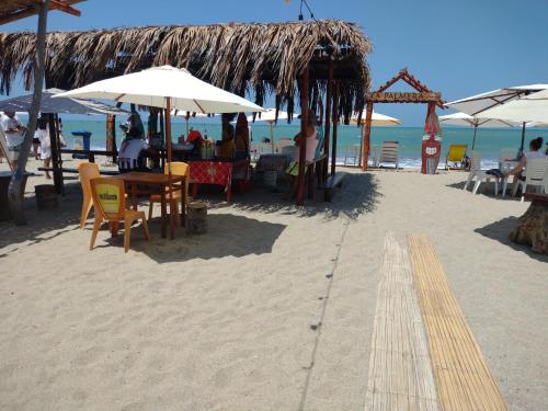 een strand met tafels en stoelen en parasols op het zand bij La palmera zorritos in Tumbes
