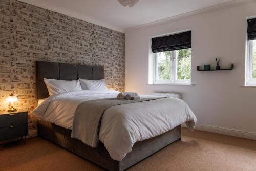 1 dormitorio con 1 cama grande y pared de ladrillo en Comfortable 4-Bedroom Home in Aylesbury Ideal for Contractors Professionals or Larger Families, en Aylesbury