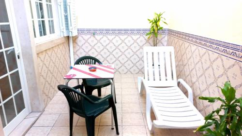 a balcony with two chairs and a table with a pizza on it at Comfortable and quiet apartment in Nazaré