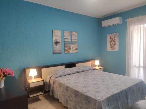 ジャルディーニ・ナクソスにあるPATI'S HOUSEの青い壁のベッドルーム1室、ベッド1台(ランプ2つ付)