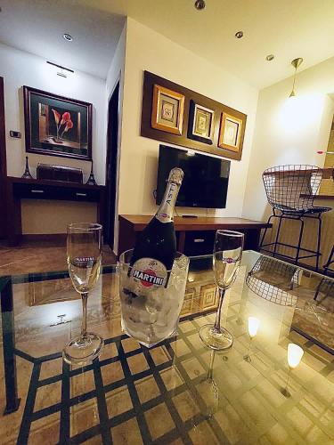 een fles wijn op een glazen tafel met twee glazen bij Nairo Aparthotel in Braşov