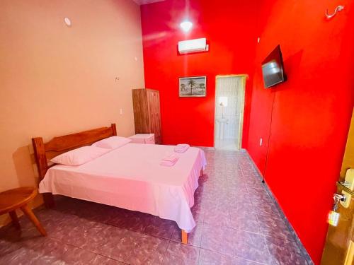 a bedroom with red walls and a white bed at Pousada Rio e Mar in Fortim