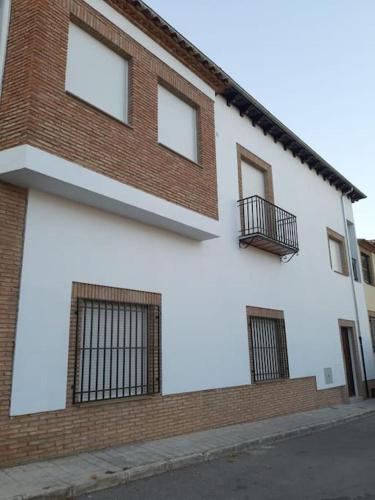 a brick and white building with windows on a street at Vive el Renacimiento: Cazuela in Baeza