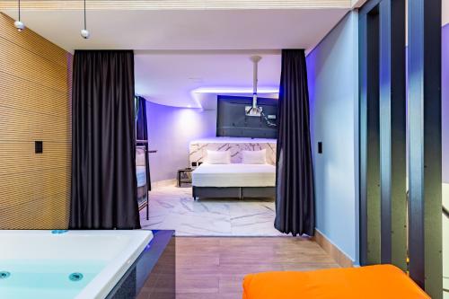a bathroom with a tub and a bed in a room at Drops Motel Brasília in Brasilia