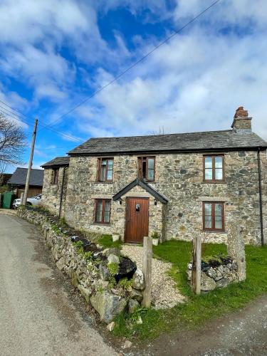 uma velha casa de pedra ao lado de uma estrada em The Old Post House - Historic Dartmoor Home em Tavistock