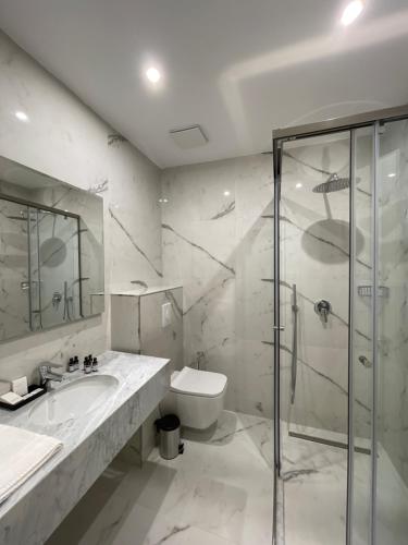 a bathroom with a shower and a sink and a toilet at Volmar Hotel in Durrës