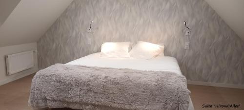 een bed met witte lakens en kussens in een kamer bij A la Lueur des Prés 