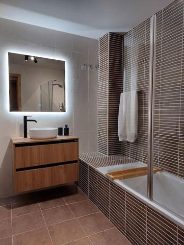 a bathroom with a tub and a sink and a mirror at Acogedor dúplex en el Valle de Aran in Caneján