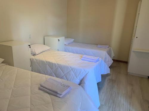 a room with three beds with towels on them at Pousada Lazúli in Macaé
