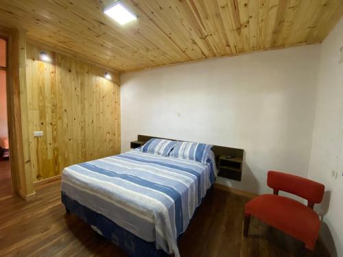 a bedroom with a bed and a red chair at Complejo Paranay in Puerto Paranay