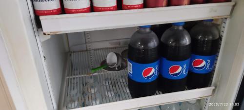 a refrigerator filled with bottles of soda at EL DORADO POUSADA in Barcelos