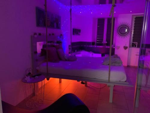 una camera da letto con un letto con luci viola di Appartement Lit Suspendu a Masevaux