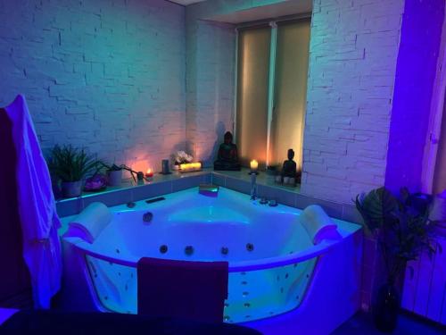 una grande vasca da bagno in una stanza con luci viola di Appartement Lit Suspendu a Masevaux