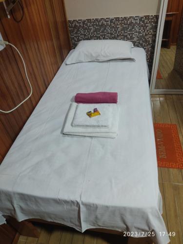 a bed with white sheets and a towel on it at EL DORADO POUSADA in Barcelos