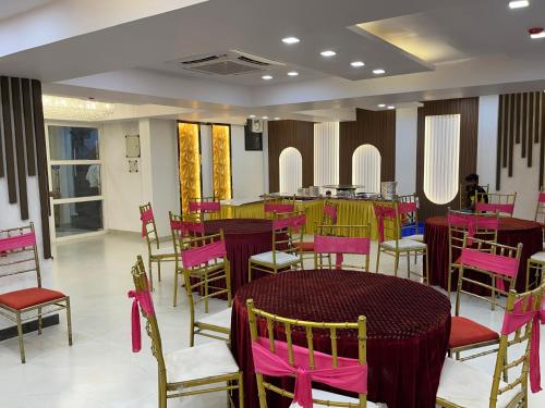 uma sala de jantar com mesas e cadeiras cor-de-rosa e amarelas em Hotel Cosmopolitan Rooms & Banquet em Allahabad