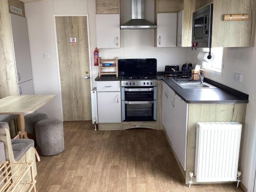 a small kitchen with a stove and a refrigerator at Staycation For You (Kent) in Leysdown-on-Sea