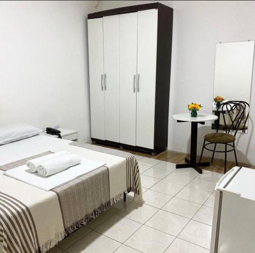 a bedroom with a bed and a table and a cabinet at Majestic Hotel in Campina Grande