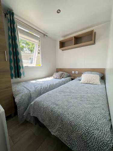 - 2 lits dans une petite chambre avec fenêtre dans l'établissement Mobil-Home 4 étoiles avec piscine proche de Blois, à Onzain