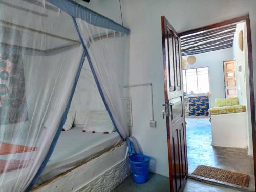 1 dormitorio con cama con dosel en una habitación en Kacho House, en Jambiani
