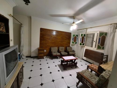 ein Wohnzimmer mit einem TV, Stühlen und einem Tisch in der Unterkunft Rental home ismailia in Ismailia