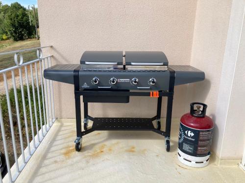 a barbecue grill on a balcony with a fire extinguisher at Chez Marie et Fabrice in La Marque