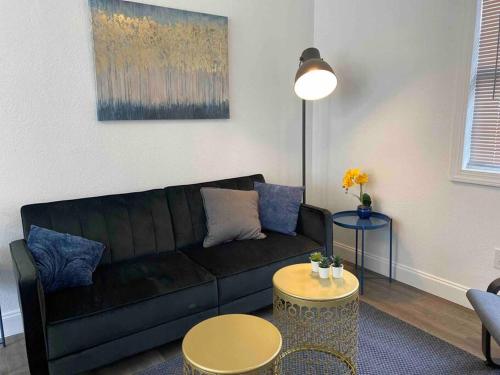 a living room with a black couch and a table at Contemporary 1-Bedroom Private Bungalow Walk to Armature & Riverwalk in Tampa