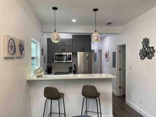 a kitchen with two bar stools at a counter at Contemporary 1-Bedroom Private Bungalow Walk to Armature & Riverwalk in Tampa