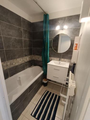 a bathroom with a tub and a sink and a mirror at Appartement T2 en résidence sécurisée in Oloron-Sainte-Marie