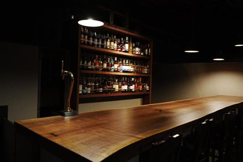 a bar with a wooden counter and a shelf of alcohol at root hakone in Hakone