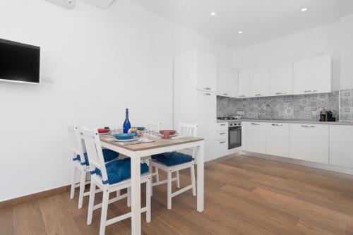 cocina blanca con mesa blanca y sillas en Due Golfi Apartment, en SantʼAgata sui Due Golfi