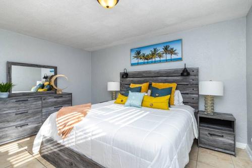 a bedroom with a large bed with yellow and blue pillows at Ocean 18 - Oceanside in Indian Harbour Beach