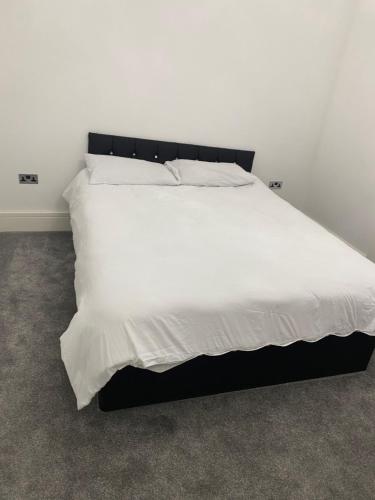 a bed with white sheets and a black headboard at Designer Apartment APT6 in Wolverhampton