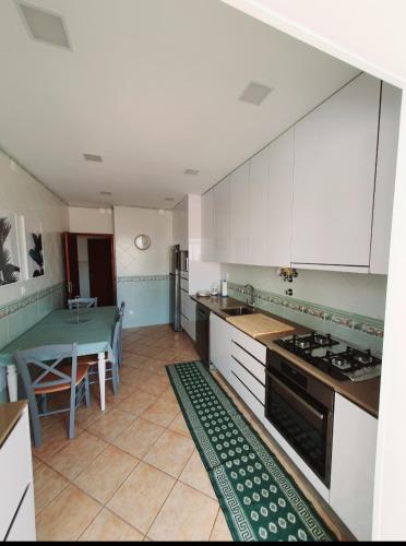 a kitchen with white cabinets and a table and a stove at Sea & Relax Villa Nazaré in Nazaré