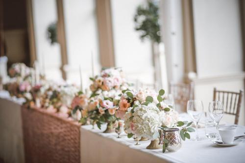 a long table with vases of flowers and wine glasses at Holiday Inn Stoke on Trent M6 Jct15 by IHG in Stoke on Trent