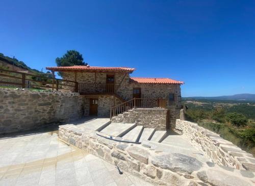 a stone house on a hill with a stone wall at Casa Rosmaninho - Izei in Chaves
